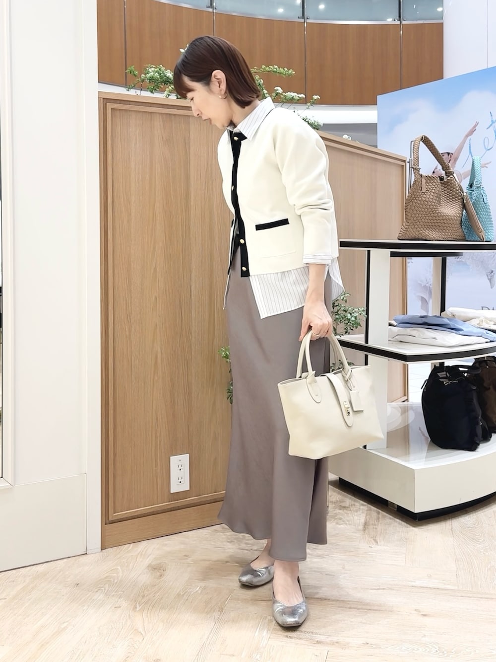 ベージュ系のトートバッグ、ホワイト系のシャツ/ブラウス、グリーン系のスカートを着用したレディースの春コーディネートの2枚目の写真