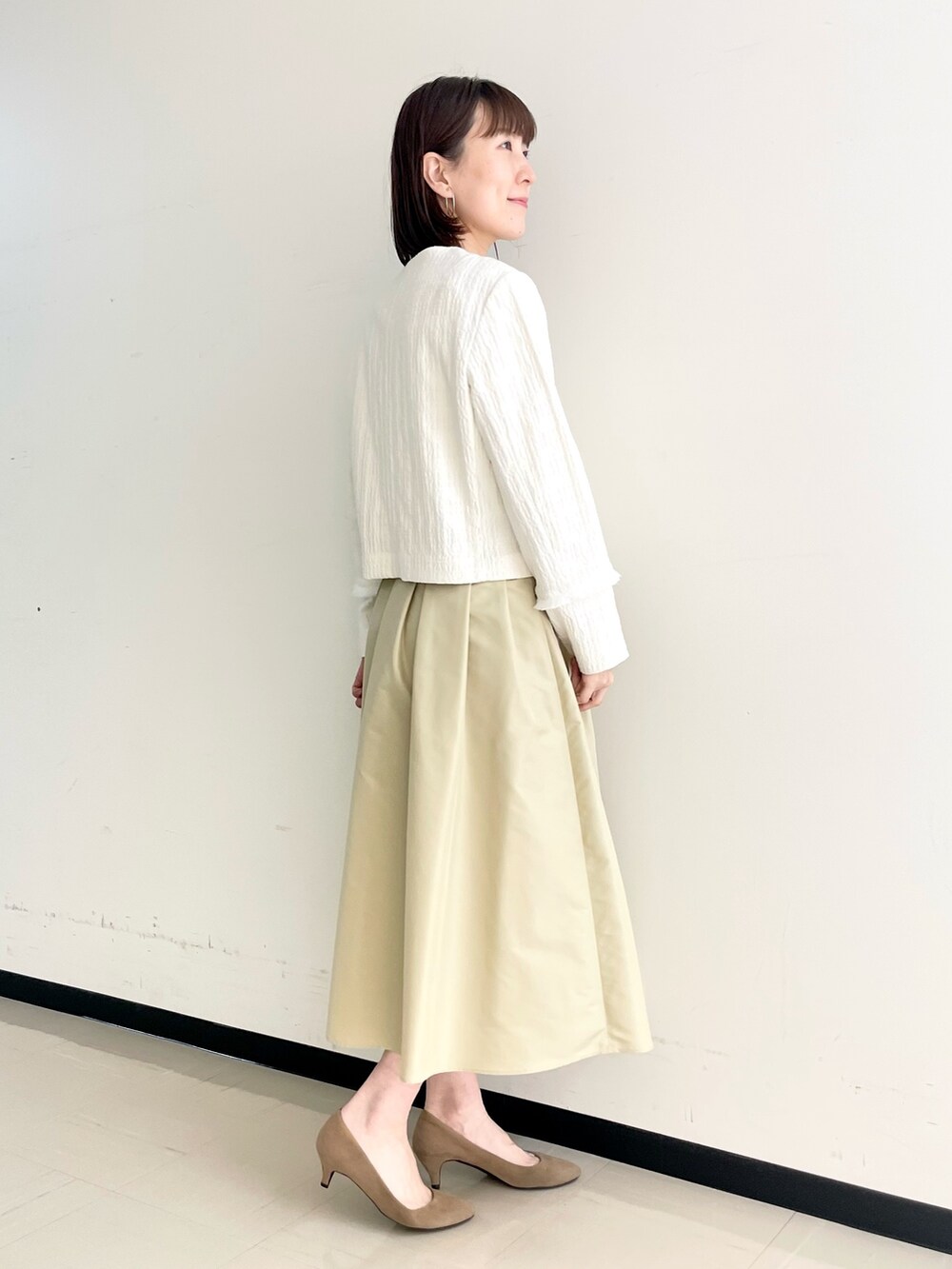 ベージュ系のスカート、ホワイト系のノーカラージャケット、ホワイト系のニット/セーターを着用したレディースの春コーディネートの8枚目の写真