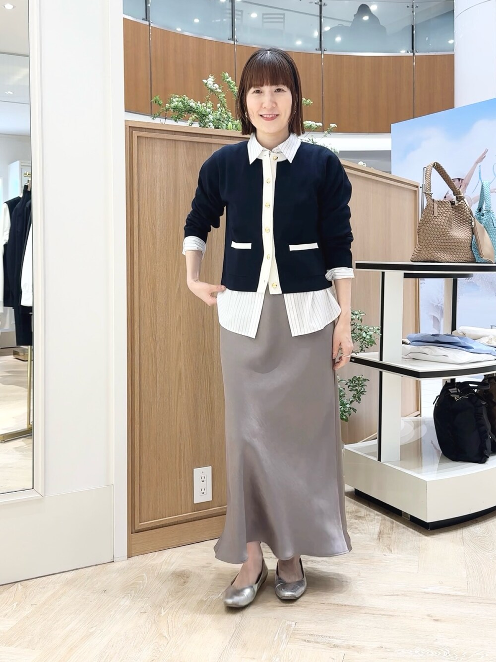 グリーン系のスカート、ベージュ系のトートバッグ、ブルー系のカーディガン/ボレロを着用したレディースの春コーディネートの5枚目の写真