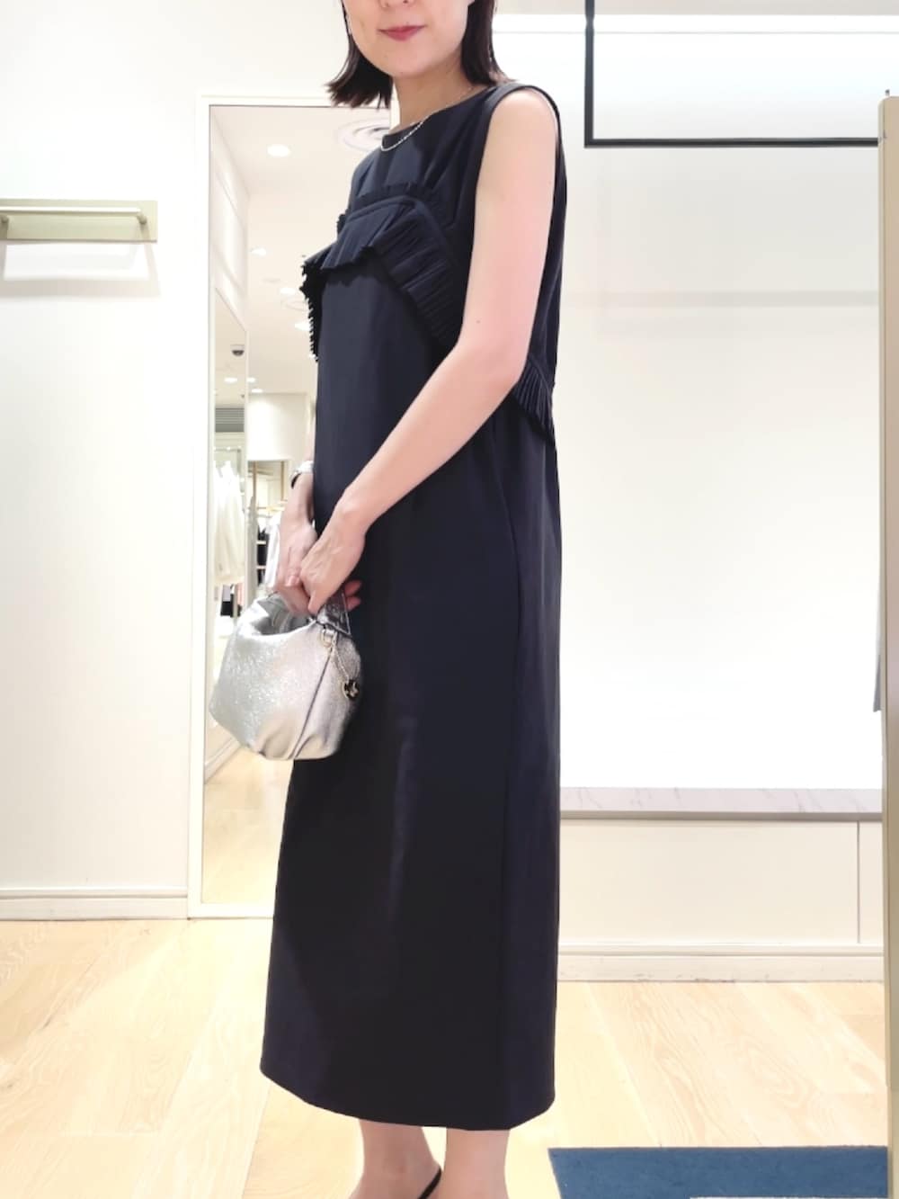 ブラック系のパンプス、ブルー系のワンピース、シルバー系のネックレスを着用したレディースの春コーディネートの6枚目の写真