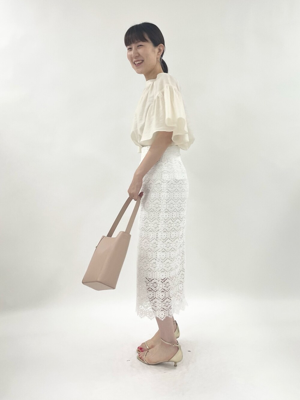 ゴールド系のサンダル、ピンク系のトートバッグ、ホワイト系のシャツ/ブラウスを着用したレディースの春コーディネートの2枚目の写真