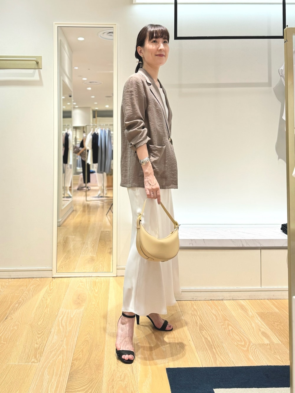 グリーン系のテーラードジャケット、ホワイト系のタンクトップ、ホワイト系のスカートを着用したレディースの夏コーディネートの3枚目の写真