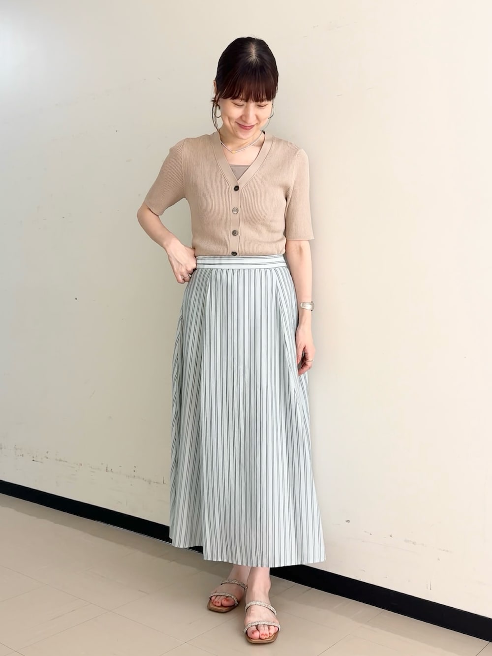 ブルー系のスカート、ベージュ系のカーディガン/ボレロ、ベージュ系のタンクトップを着用したレディースの夏コーディネートの5枚目の写真