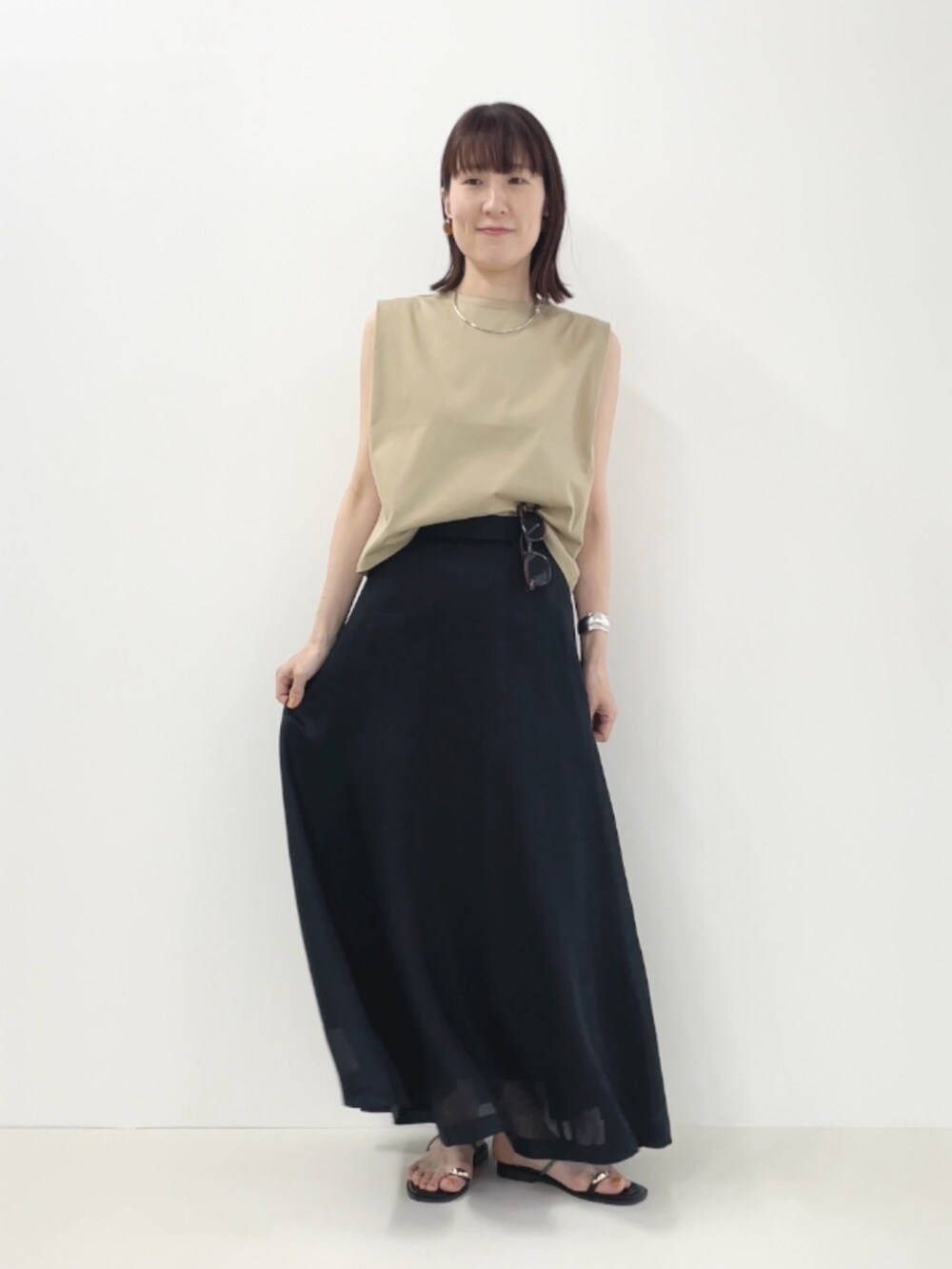 ブラック系のサンダル、ベージュ系のTシャツ/カットソー、ブラック系のスカートを着用したレディースの夏コーディネートの2枚目の写真