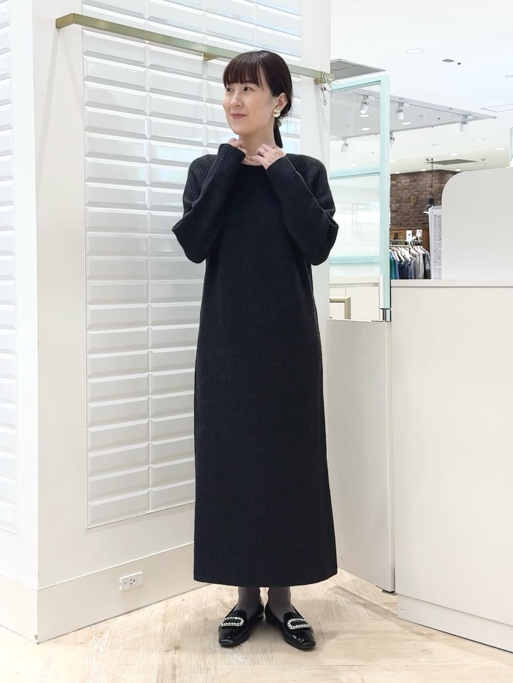 グレー系のワンピース、ゴールド系のイヤリング、ホワイト系のネックレスを着用したレディースの冬コーディネートの6枚目の写真