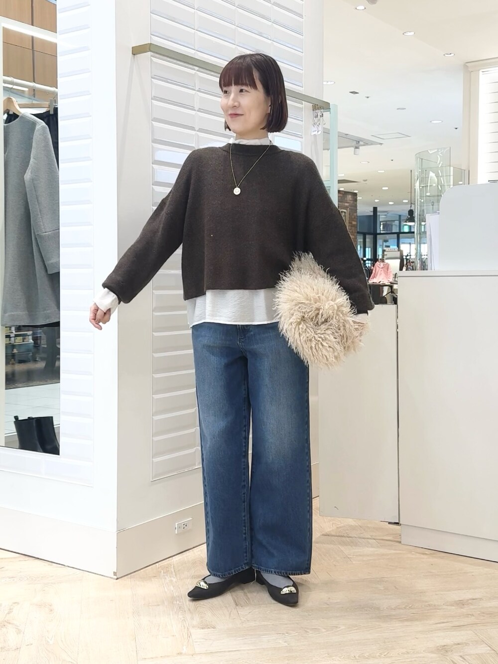 ベージュ系のショルダーバッグ、ホワイト系のシャツ/ブラウス、ブラウン系のニット/セーターを着用したレディースの冬コーディネートの8枚目の写真