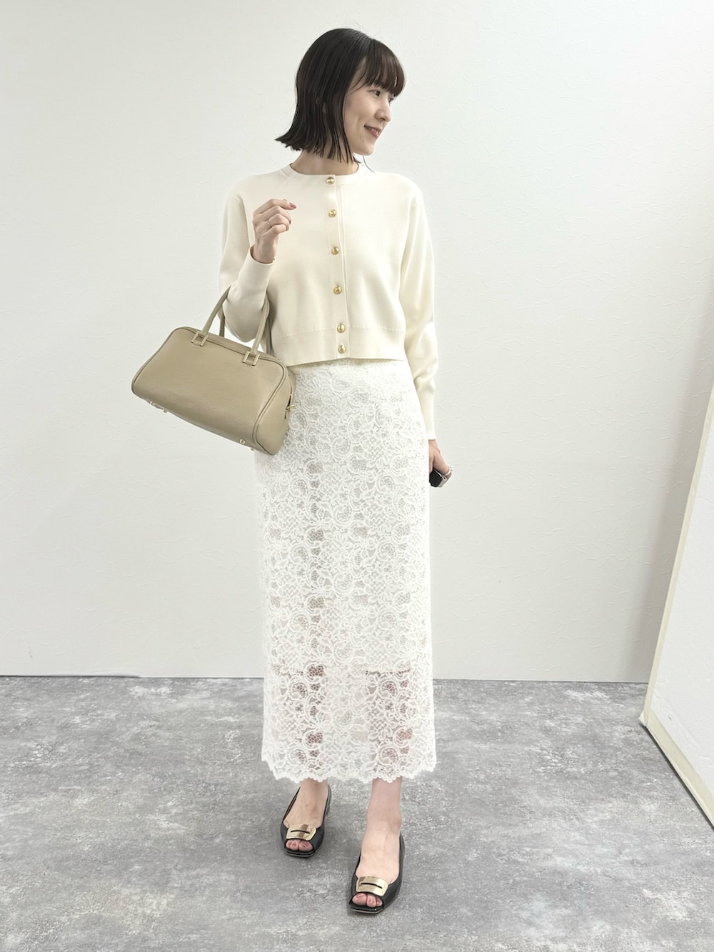 ホワイト系のカーディガン/ボレロ、ベージュ系のショルダーバッグ、ホワイト系のスカートを着用したレディースの秋コーディネートの3枚目の写真