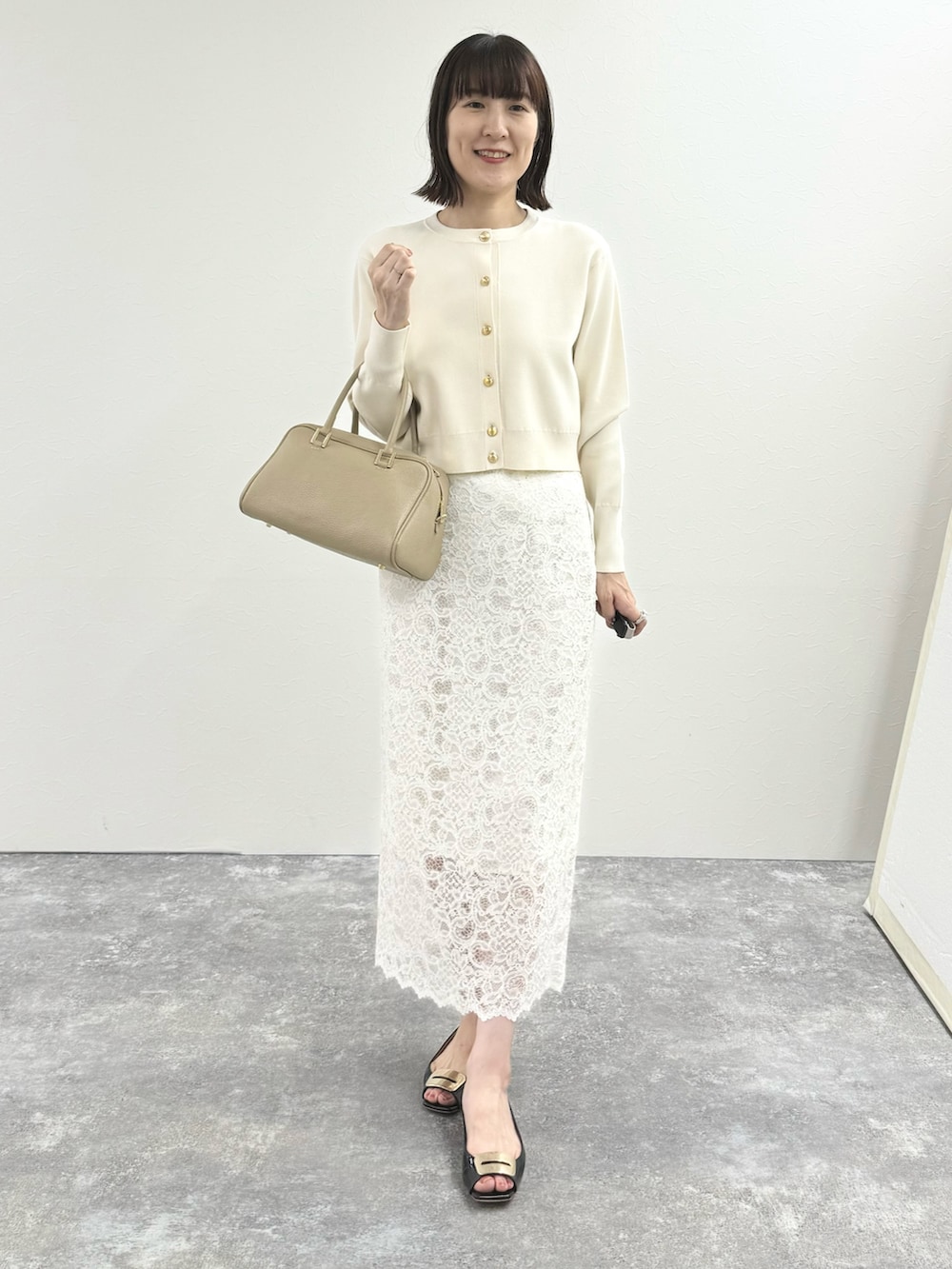 ホワイト系のカーディガン/ボレロ、ベージュ系のショルダーバッグ、ホワイト系のスカートを着用したレディースの秋コーディネートの2枚目の写真