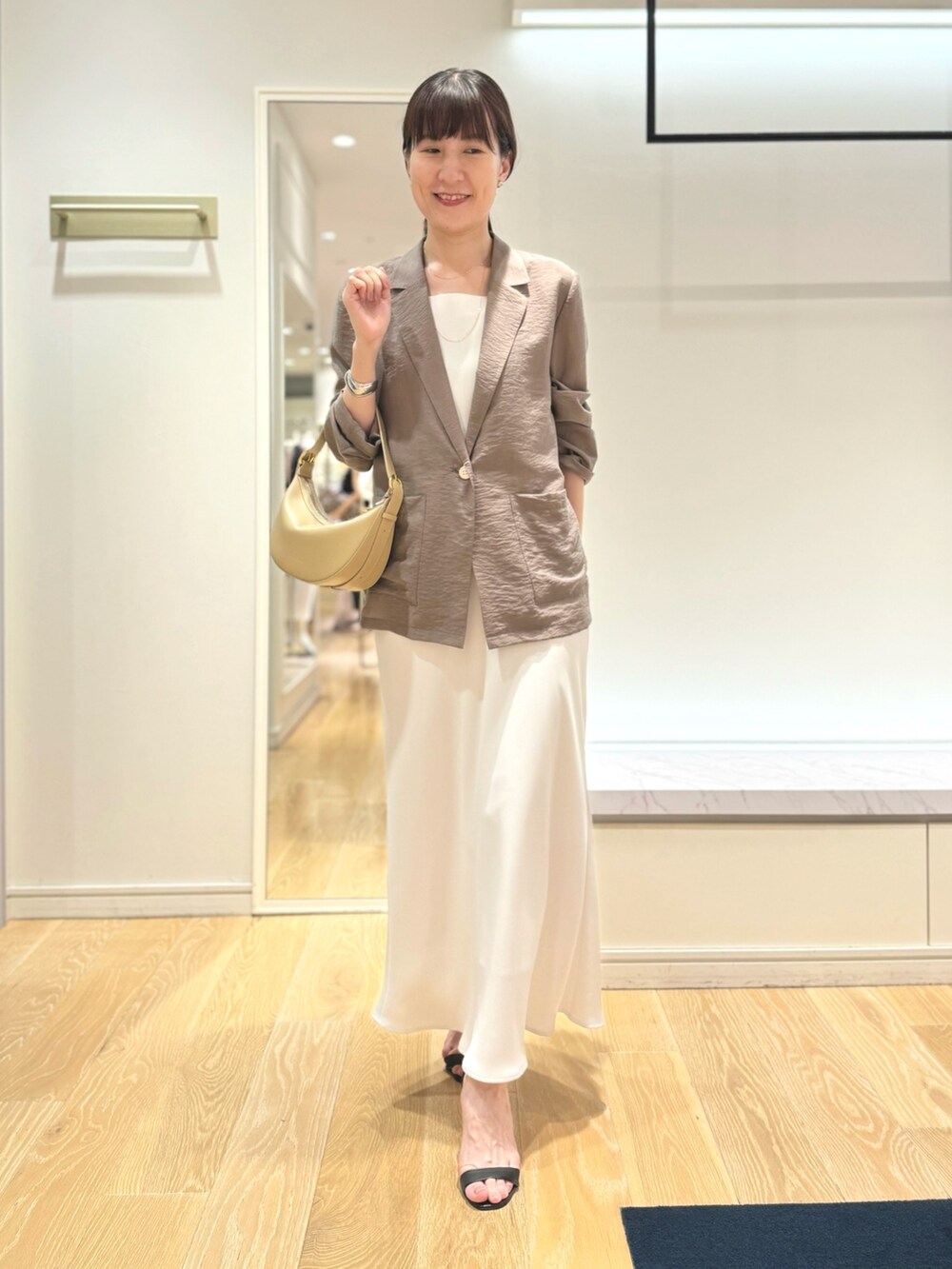 グリーン系のテーラードジャケット、ホワイト系のタンクトップ、ホワイト系のスカートを着用したレディースの夏コーディネートの6枚目の写真