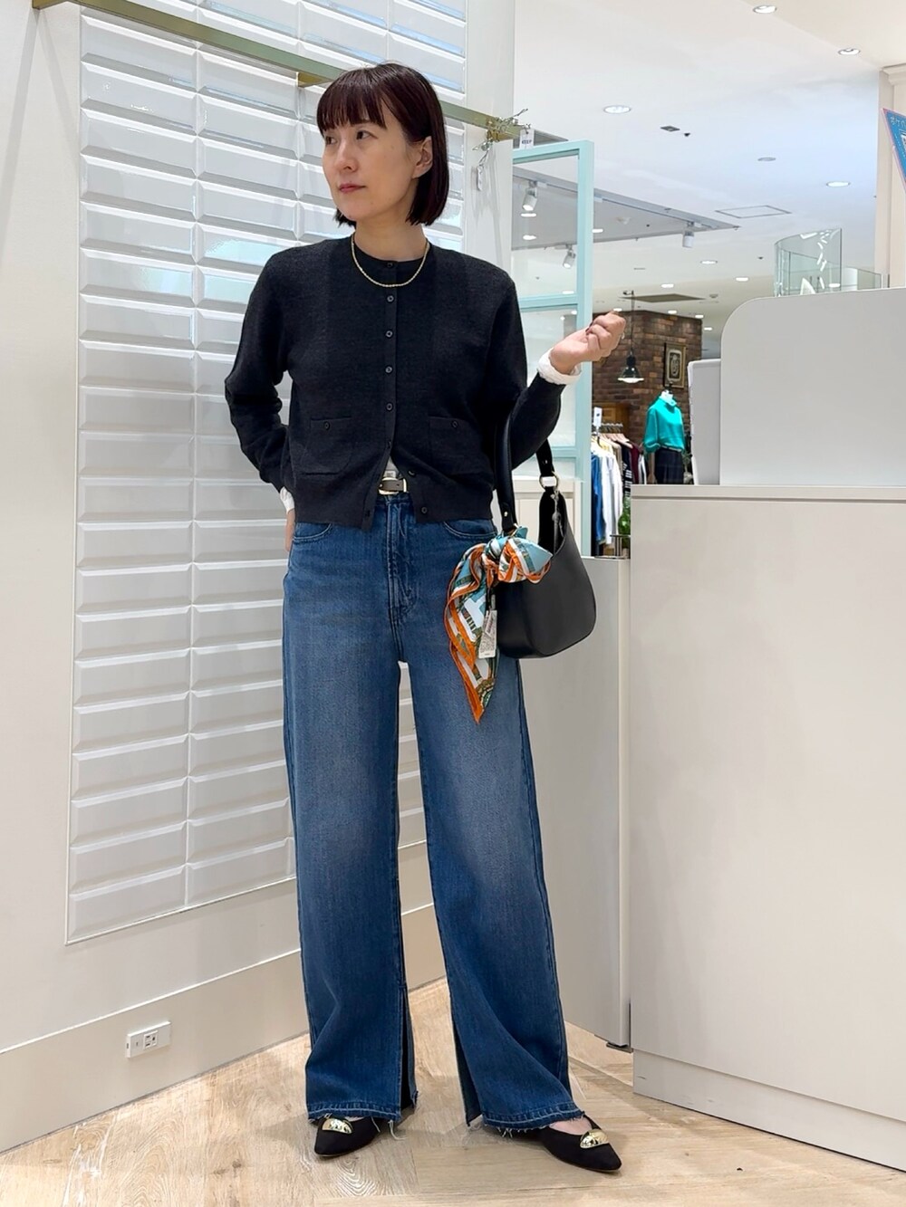 ブルー系のデニムパンツ、グレー系のカーディガン/ボレロ、ホワイト系のTシャツ/カットソーを着用したレディースの秋コーディネートの6枚目の写真