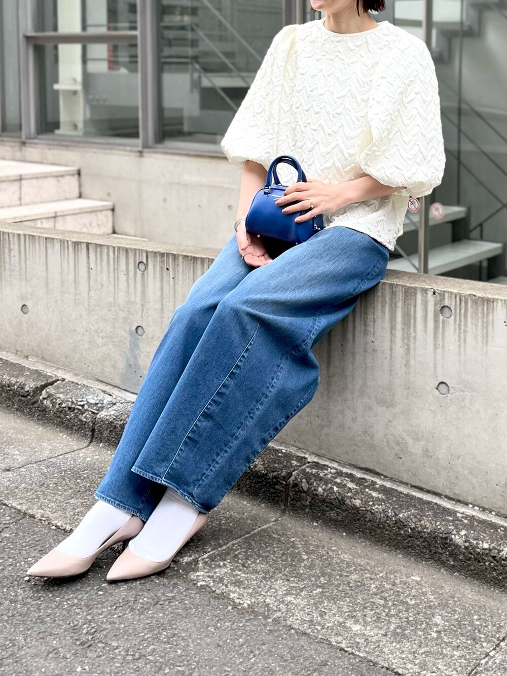 ブルー系のボストンバッグ、ブルー系のデニムパンツ、ホワイト系のシャツ/ブラウスを着用したレディースの冬コーディネートの2枚目の写真