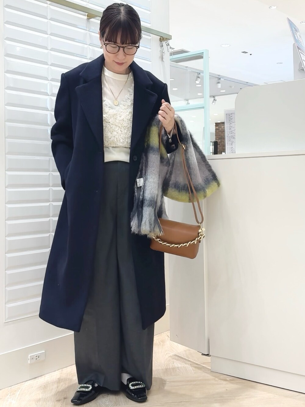 グレー系のその他パンツ、ブルー系のチェスターコート、ホワイト系のベストを着用したレディースの秋コーディネートの9枚目の写真