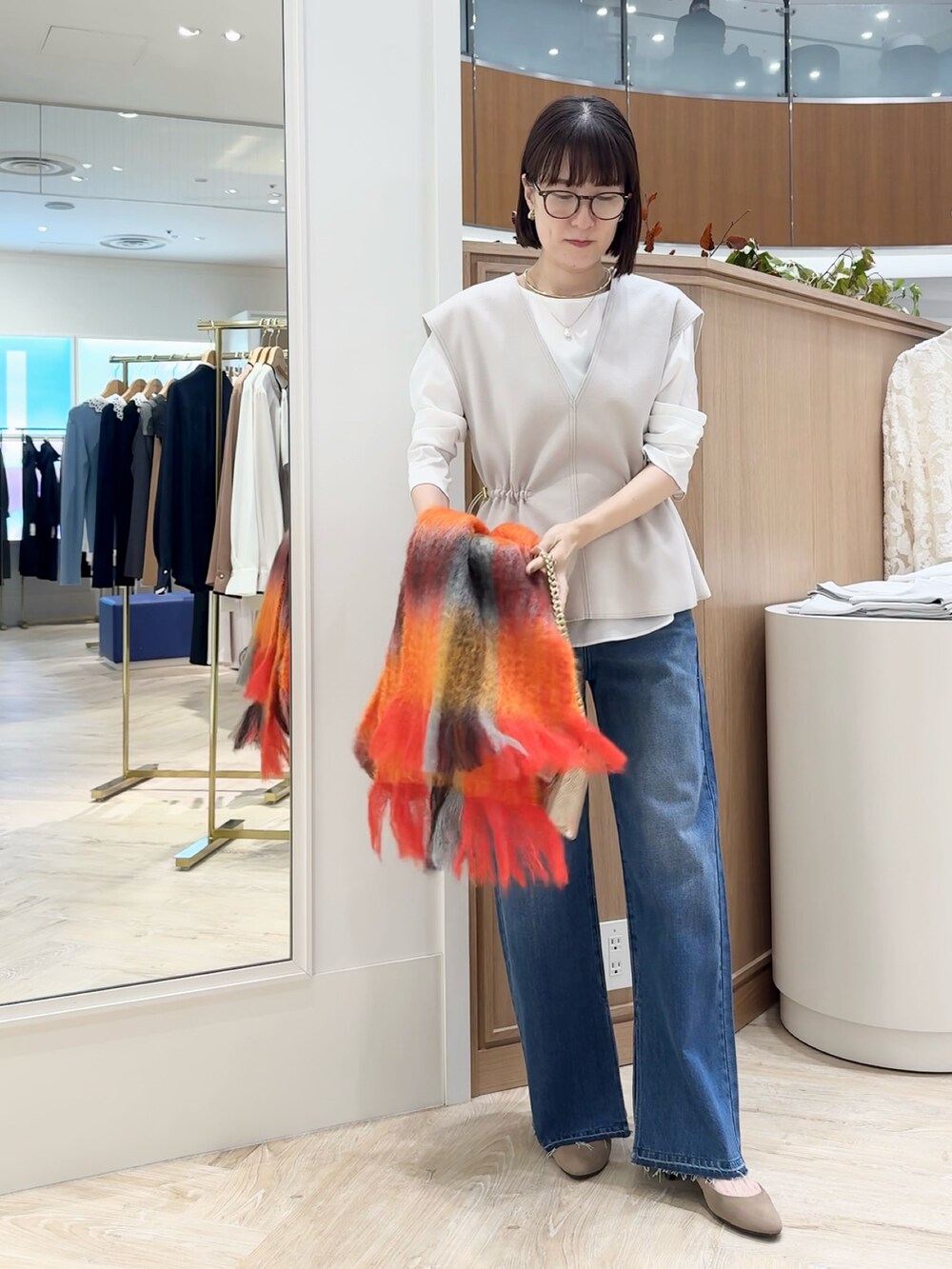 ブルー系のデニムパンツ、ベージュ系のベスト、ホワイト系のシャツ/ブラウスを着用したレディースの秋コーディネートの5枚目の写真