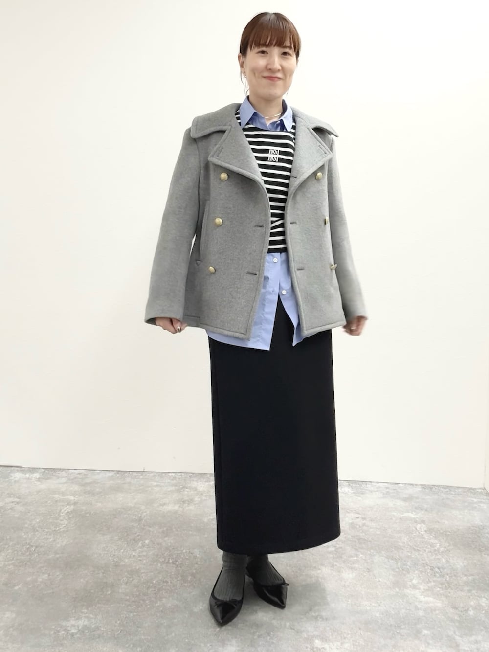 ブラック系のスカート、ブラック系のTシャツ/カットソー、グレー系のピーコートを着用したレディースの秋コーディネートの2枚目の写真