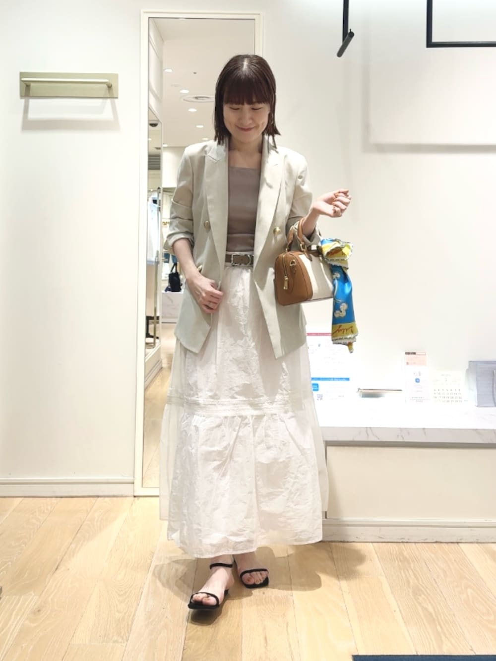 ベージュ系のテーラードジャケット、ベージュ系のタンクトップ、ブラウン系のボストンバッグを着用したレディースの春コーディネートの6枚目の写真