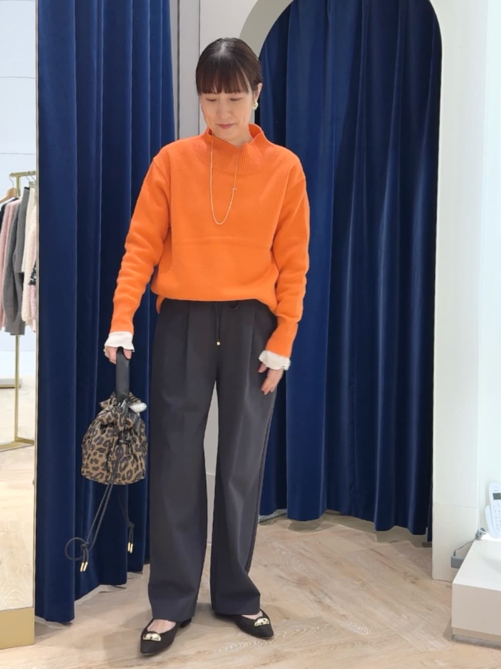 オレンジ系のニット/セーター、グレー系のその他パンツ、ホワイト系のTシャツ/カットソーを着用したレディースの冬コーディネートの6枚目の写真