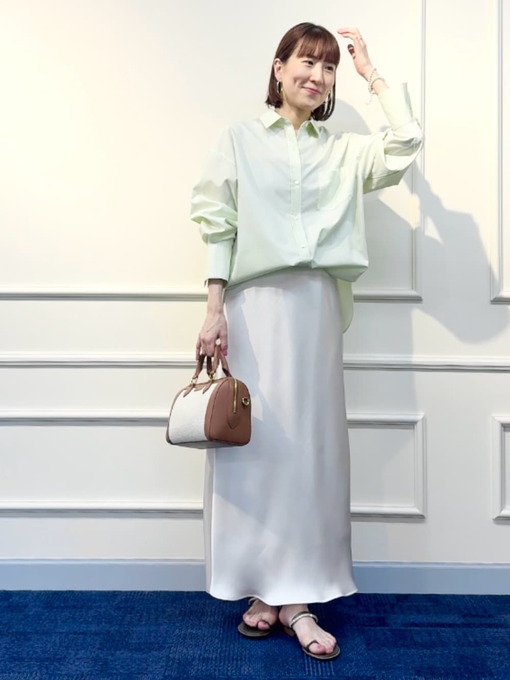 ブラウン系のボストンバッグ、ホワイト系のスカート、グリーン系のシャツ/ブラウスを着用したレディースの冬コーディネートの5枚目の写真