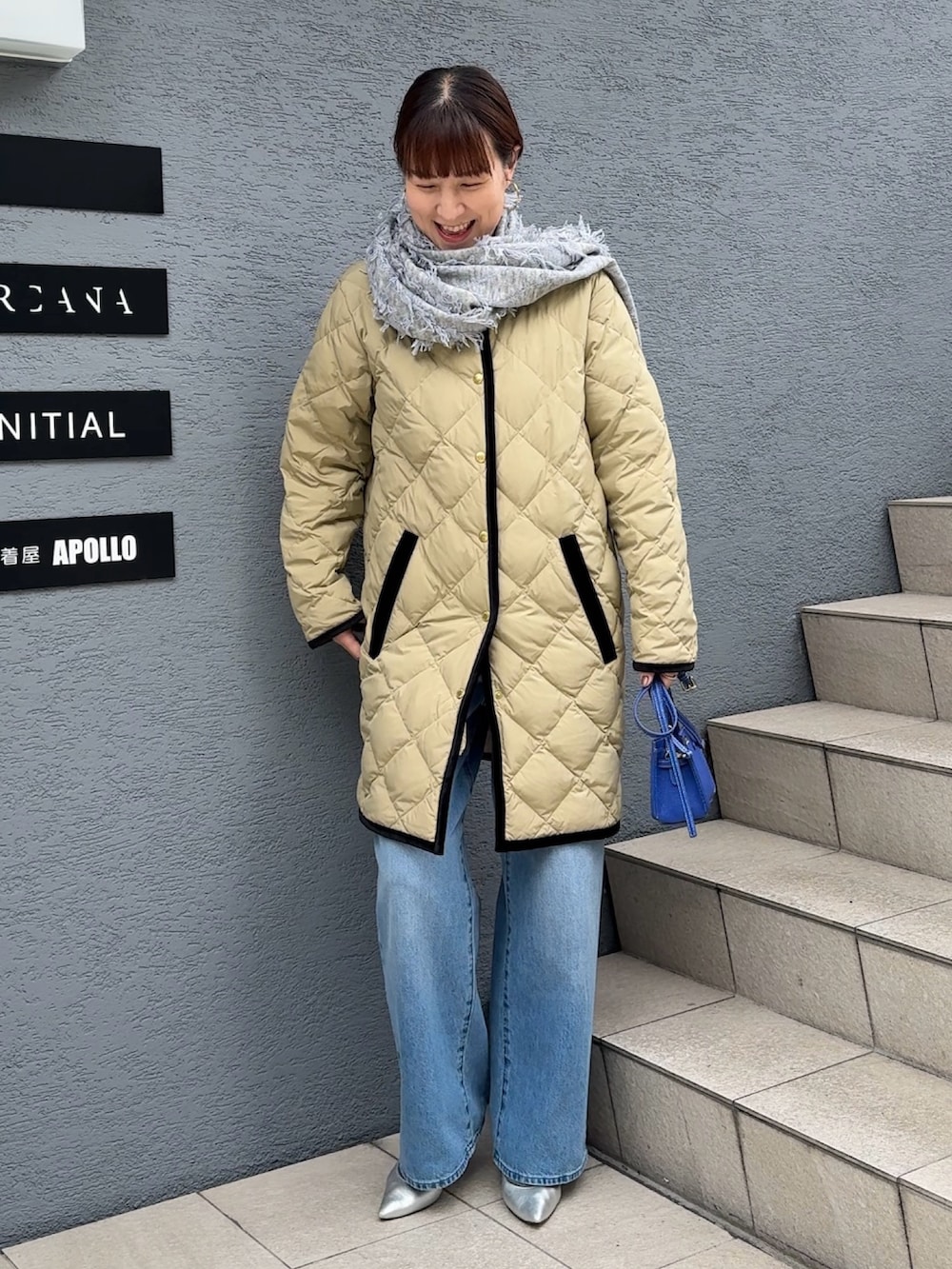 ブルー系のデニムパンツ、ブルー系のショルダーバッグ、ベージュ系のダウンジャケット/コートを着用したレディースの秋コーディネートの2枚目の写真