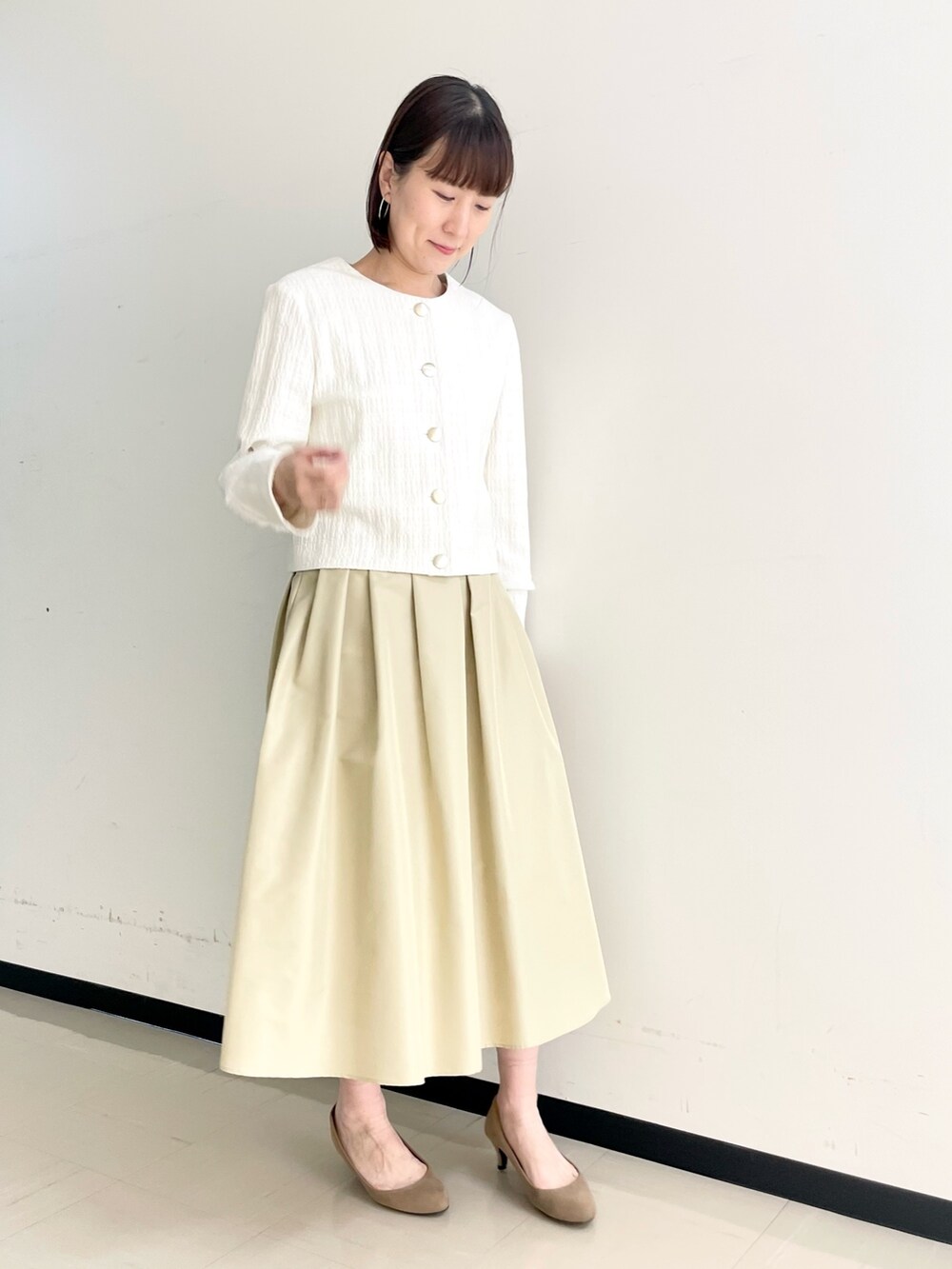 ベージュ系のスカート、ホワイト系のノーカラージャケット、ホワイト系のニット/セーターを着用したレディースの春コーディネートの9枚目の写真