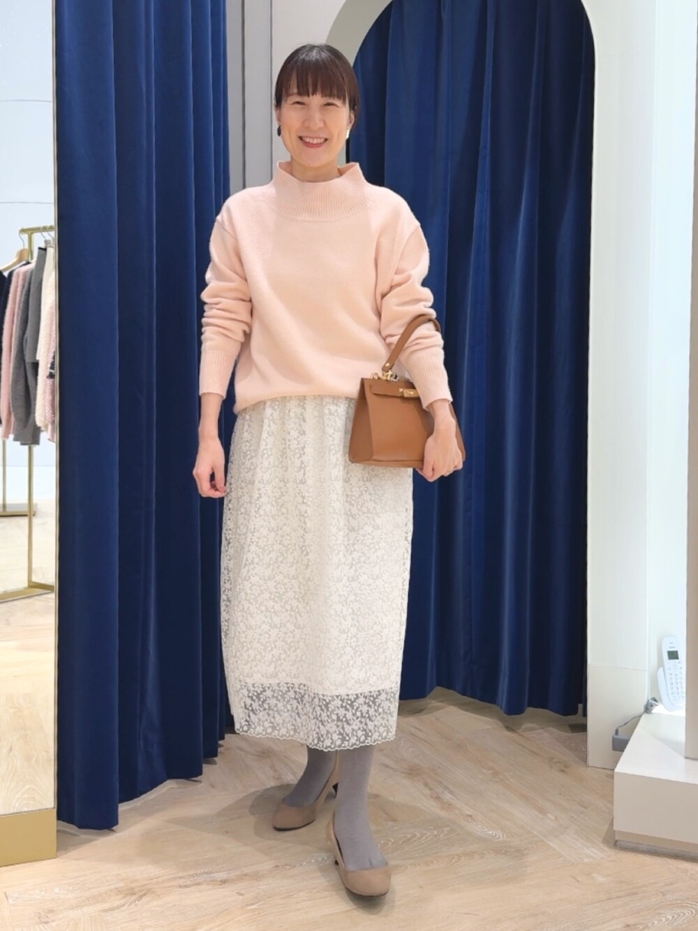 ピンク系のニット/セーター、イエロー系のショルダーバッグ、ホワイト系のスカートを着用したレディースの冬コーディネートの10枚目の写真