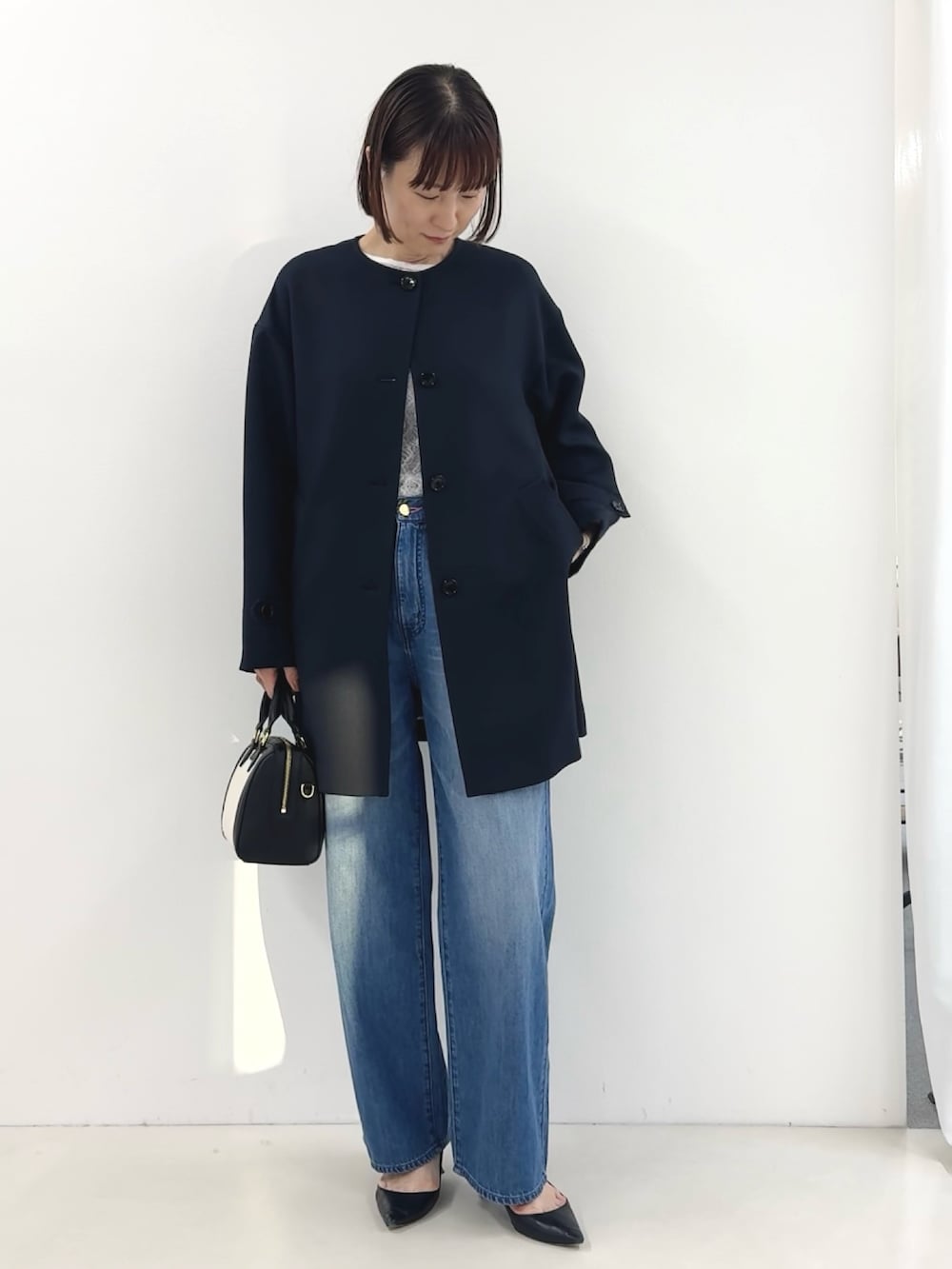 ブラック系のボストンバッグ、ホワイト系のTシャツ/カットソー、ブルー系のステンカラーコートを着用したレディースの冬コーディネートの7枚目の写真