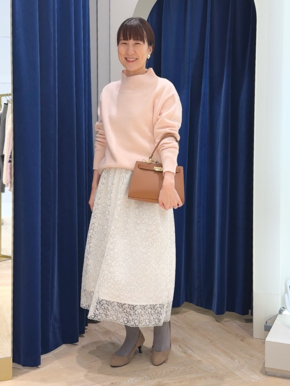 ピンク系のニット/セーター、イエロー系のショルダーバッグ、ホワイト系のスカートを着用したレディースの冬コーディネートの4枚目の写真