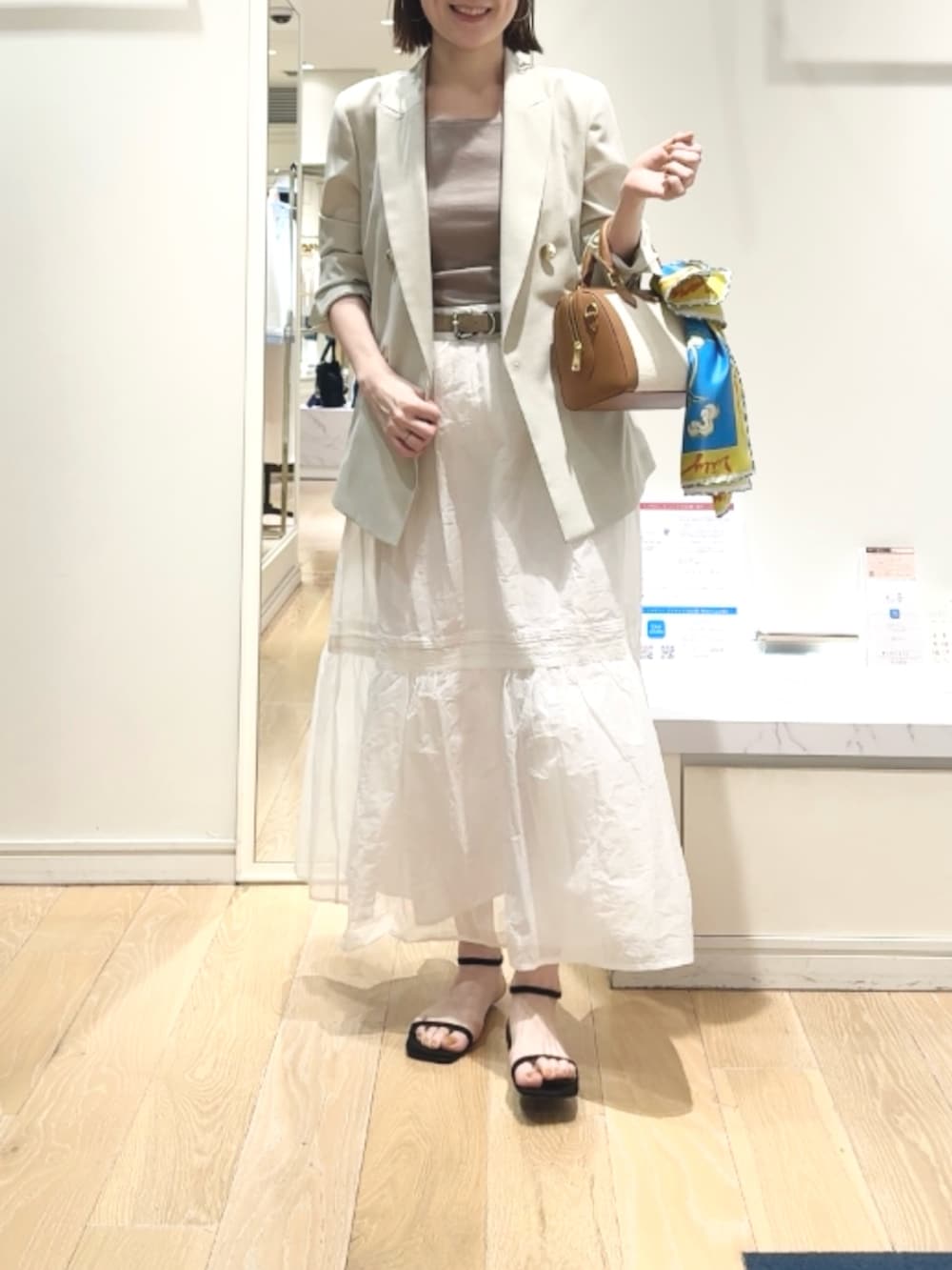 ベージュ系のテーラードジャケット、ベージュ系のタンクトップ、ブラウン系のボストンバッグを着用したレディースの春コーディネートの8枚目の写真