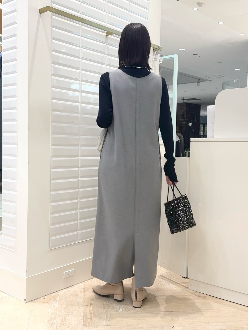 グレー系のワンピース、ブラック系のショルダーバッグ、ブルー系のTシャツ/カットソーを着用したレディースの冬コーディネートの3枚目の写真