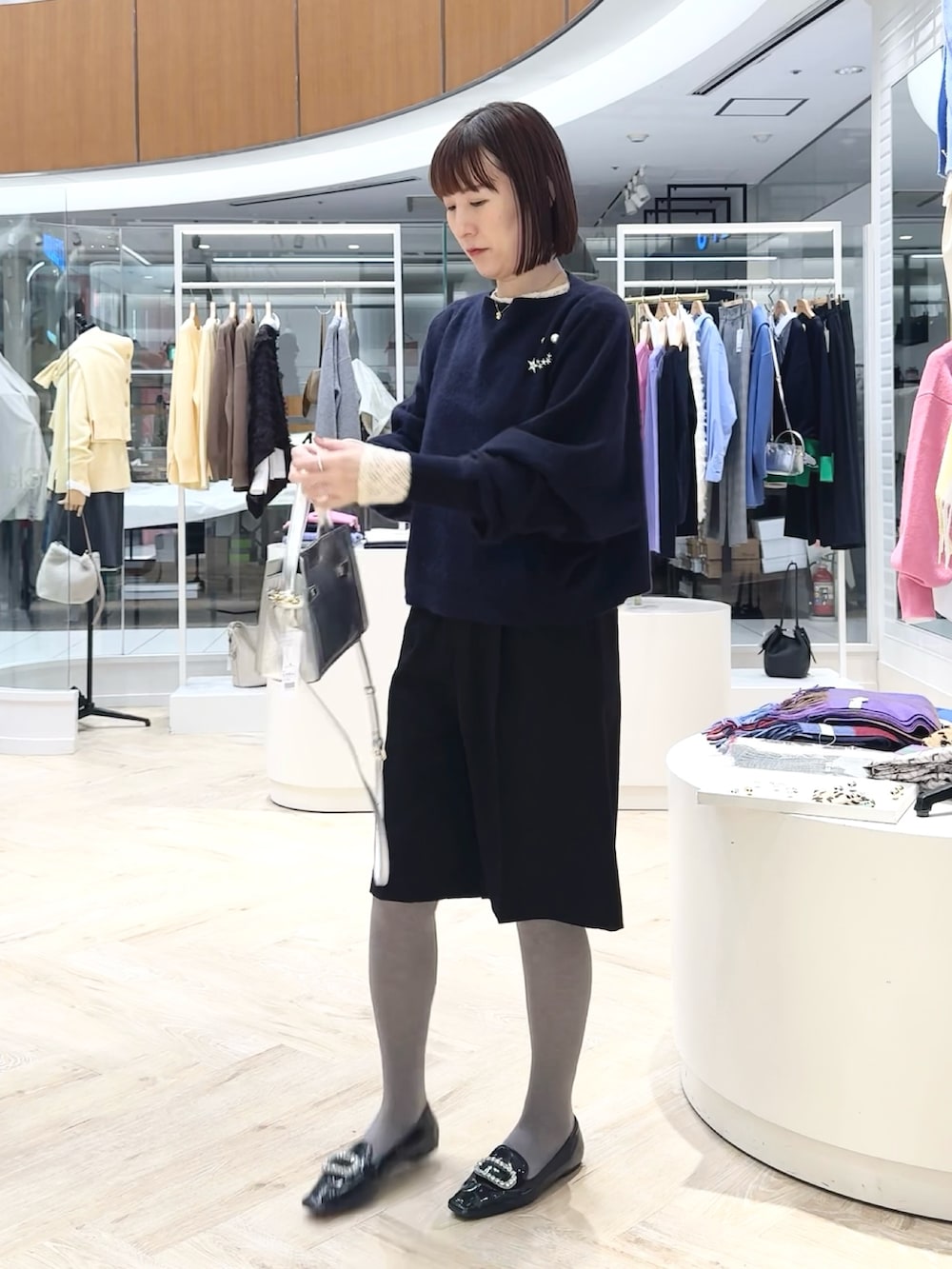 ブルー系のニット/セーター、ブラック系のその他パンツ、ホワイト系のカーディガン/ボレロを着用したレディースの冬コーディネートの4枚目の写真