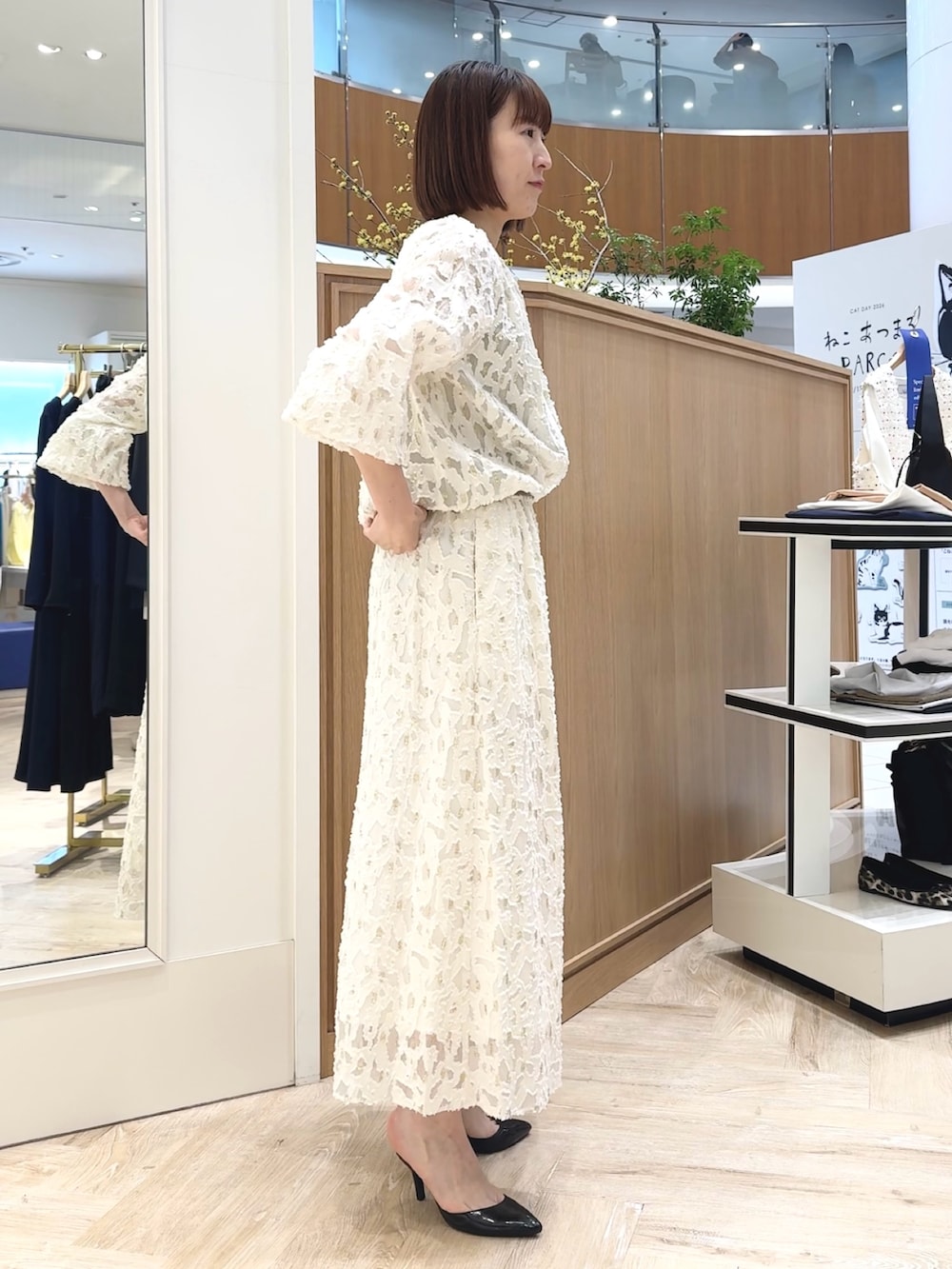 ホワイト系のショルダーバッグ、ゴールド系のタンクトップ、ホワイト系のブルゾンを着用したレディースの冬コーディネートの7枚目の写真