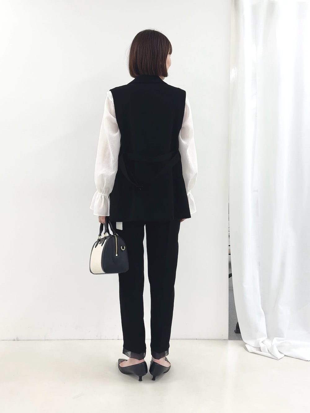 ブラック系のベスト、ホワイト系のシャツ/ブラウス、ブラック系のその他パンツを着用したレディースの冬コーディネートの6枚目の写真