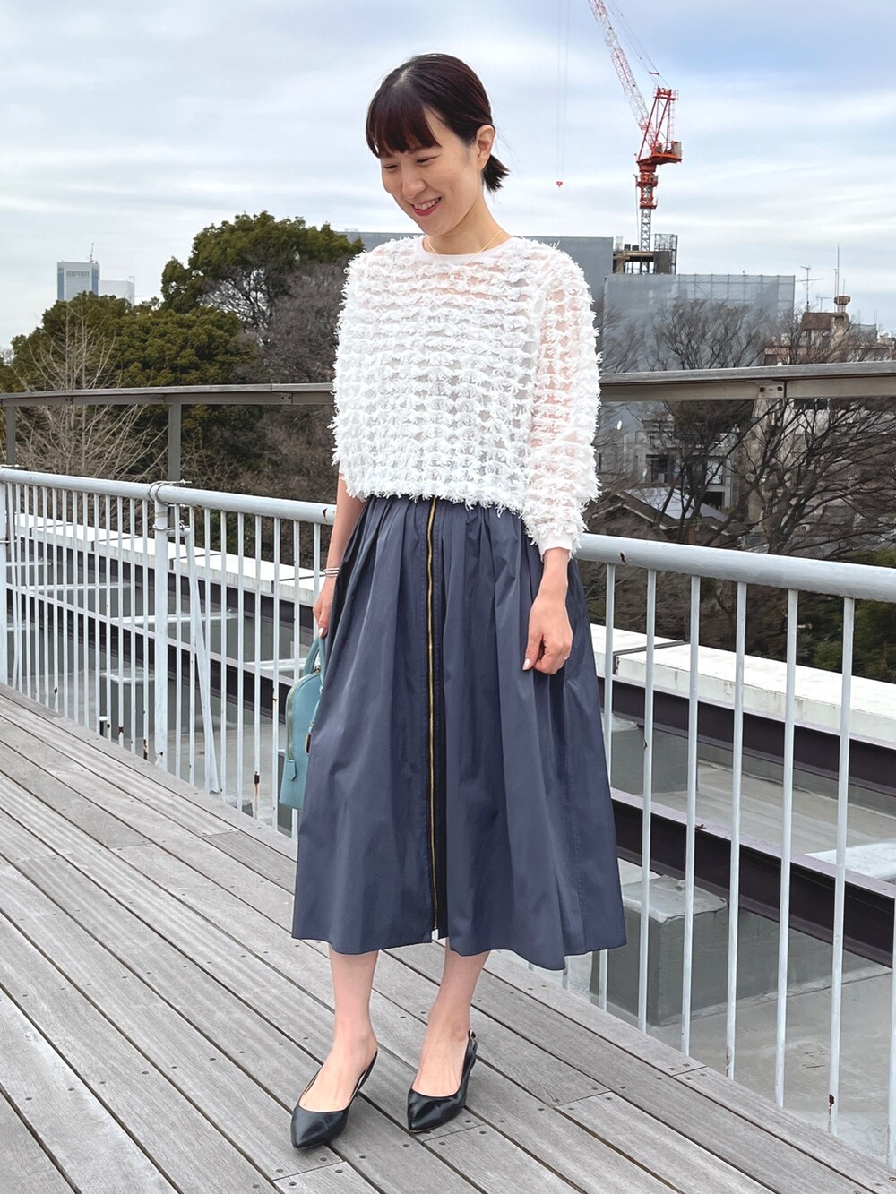 ブルー系のボストンバッグ、ブラック系のパンプス、グレー系のスカートを着用したレディースの冬コーディネートの5枚目の写真