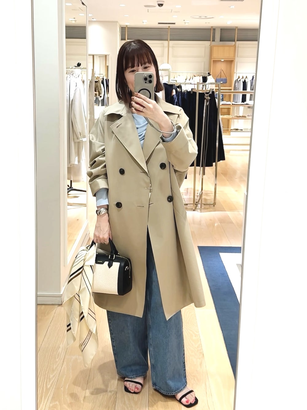 ブラック系のボストンバッグ、ブルー系のニット/セーター、ベージュ系のトレンチコートを着用したレディースの春コーディネートの8枚目の写真