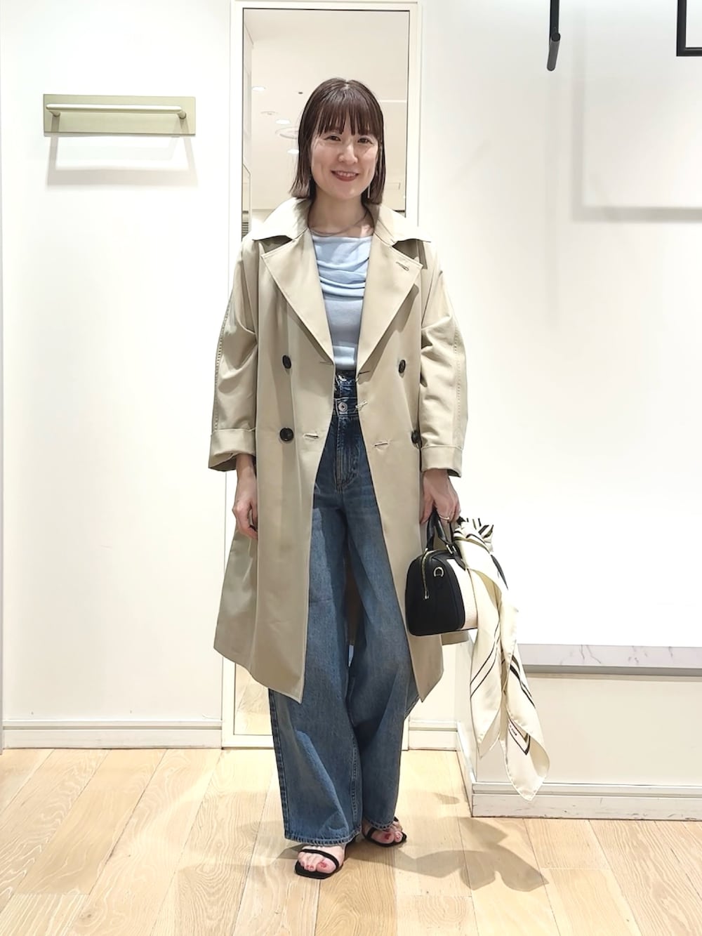 ブラック系のボストンバッグ、ブルー系のニット/セーター、ベージュ系のトレンチコートを着用したレディースの春コーディネートの9枚目の写真