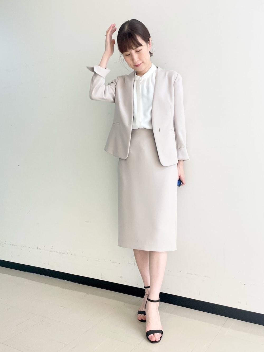 ベージュ系のスカート、ホワイト系のシャツ/ブラウス、ベージュ系のノーカラージャケットを着用したレディースの春コーディネートの2枚目の写真