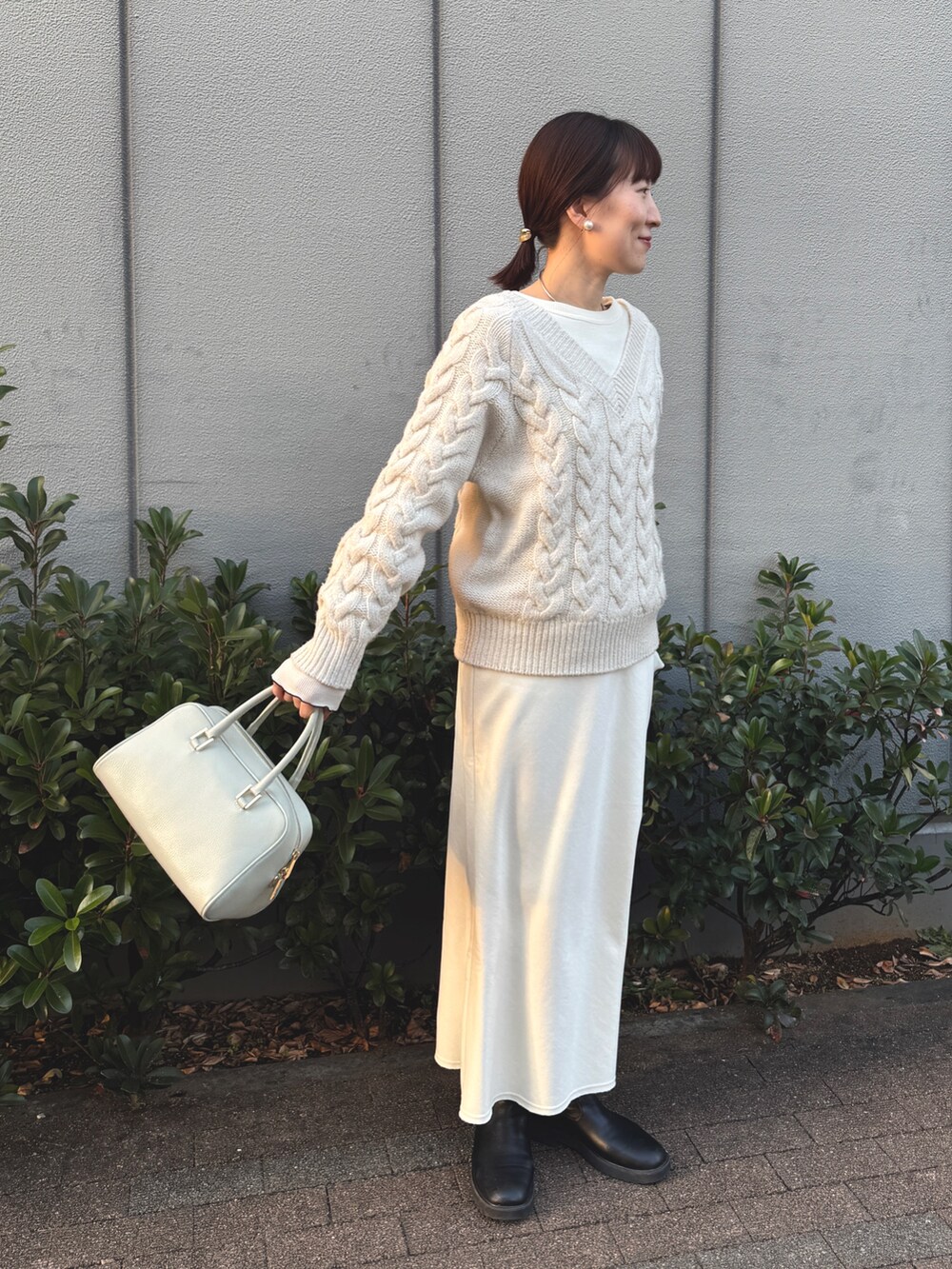 ホワイト系のニット/セーター、ホワイト系のTシャツ/カットソー、グリーン系のショルダーバッグを着用したレディースの冬コーディネートの9枚目の写真