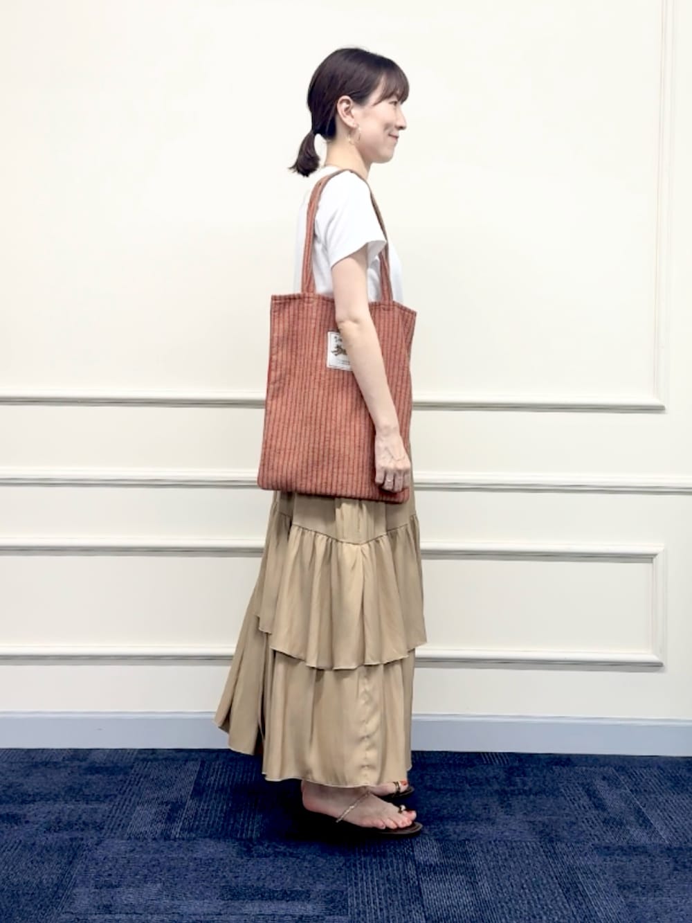 レッド系のトートバッグ、イエロー系のスカート、ホワイト系のTシャツ/カットソーを着用したレディースの夏コーディネートの3枚目の写真