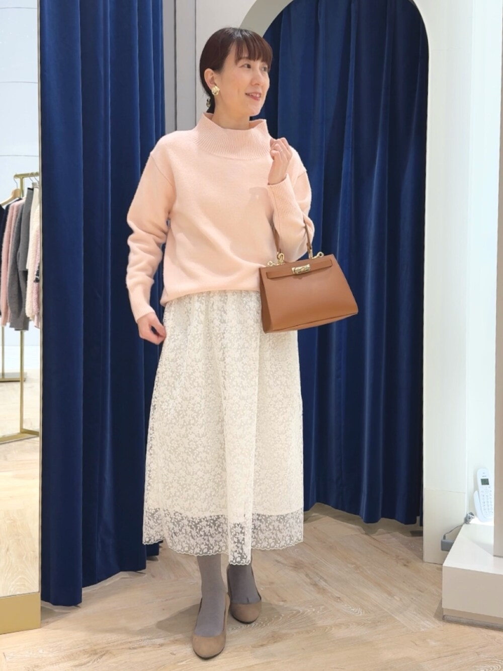 ピンク系のニット/セーター、イエロー系のショルダーバッグ、ホワイト系のスカートを着用したレディースの冬コーディネートの2枚目の写真