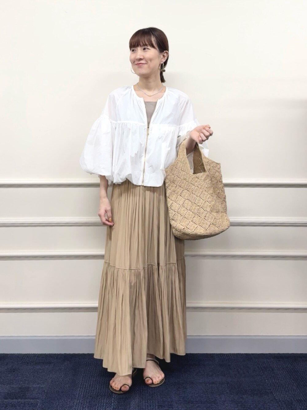 ベージュ系のスカート、ベージュ系のタンクトップ、ホワイト系のブルゾンを着用したレディースの春コーディネートの9枚目の写真