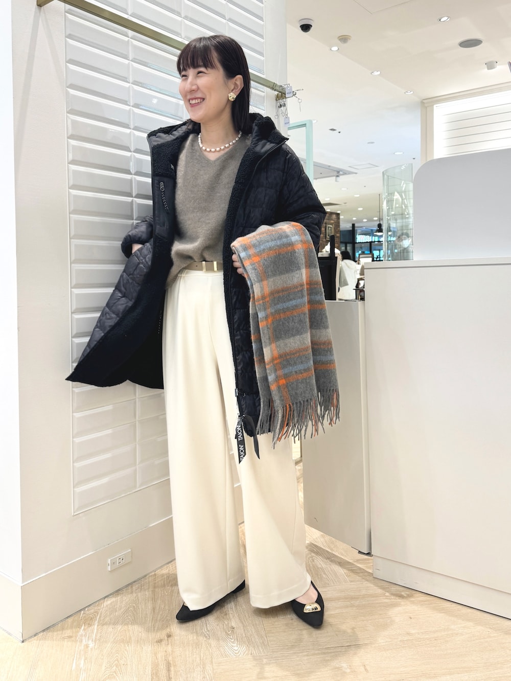 ホワイト系のその他パンツ、ベージュ系のトートバッグ、ブラック系のダウンジャケット/コートを着用したレディースの秋コーディネートの2枚目の写真