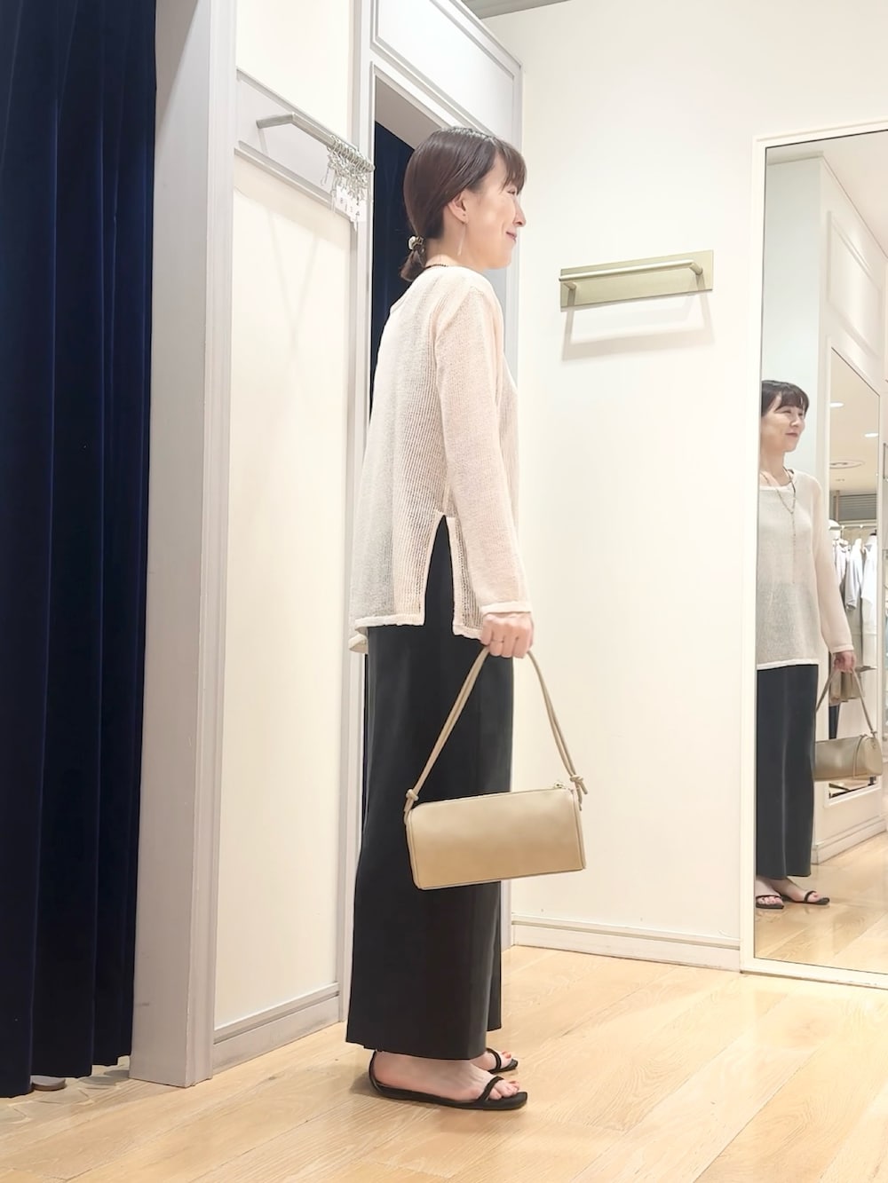 ブラック系のスカート、ベージュ系のショルダーバッグ、ホワイト系のニット/セーターを着用したレディースの夏コーディネートの3枚目の写真