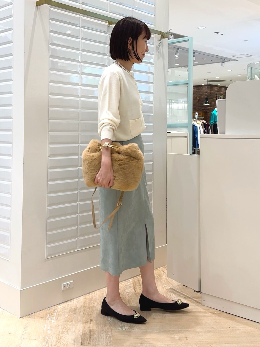 ホワイト系のカーディガン/ボレロ、ベージュ系のショルダーバッグ、グリーン系のスカートを着用したレディースの秋コーディネートの3枚目の写真