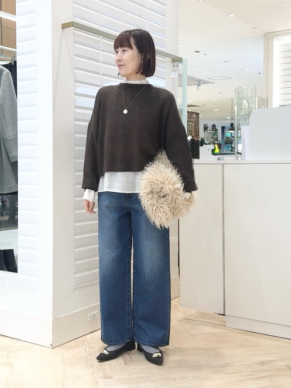 ベージュ系のショルダーバッグ、ホワイト系のシャツ/ブラウス、ブラウン系のニット/セーターを着用したレディースの冬コーディネートの4枚目の写真