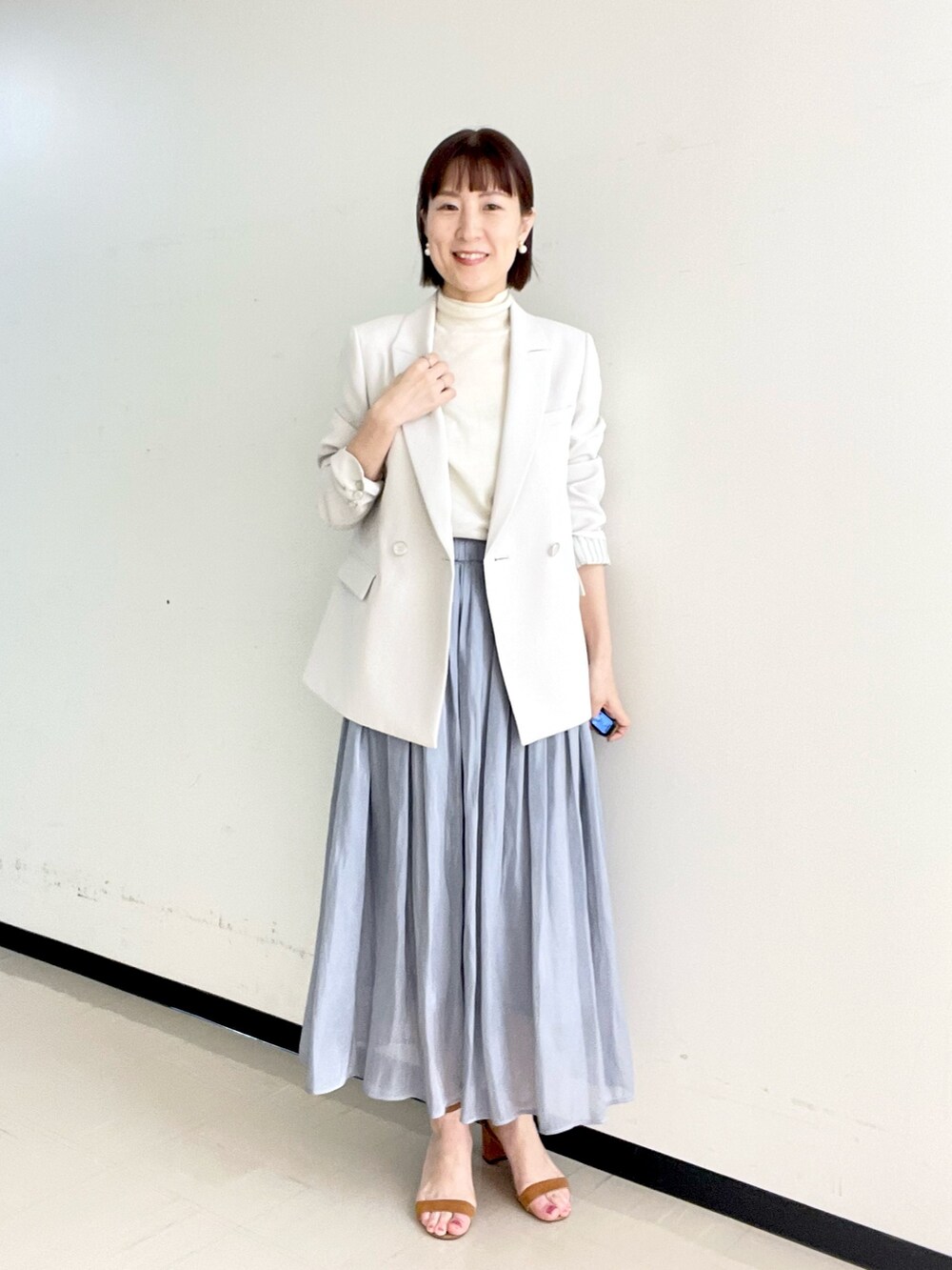 ホワイト系のニット/セーター、ベージュ系のテーラードジャケット、ゴールド系のイヤリングを着用したレディースの冬コーディネートの3枚目の写真