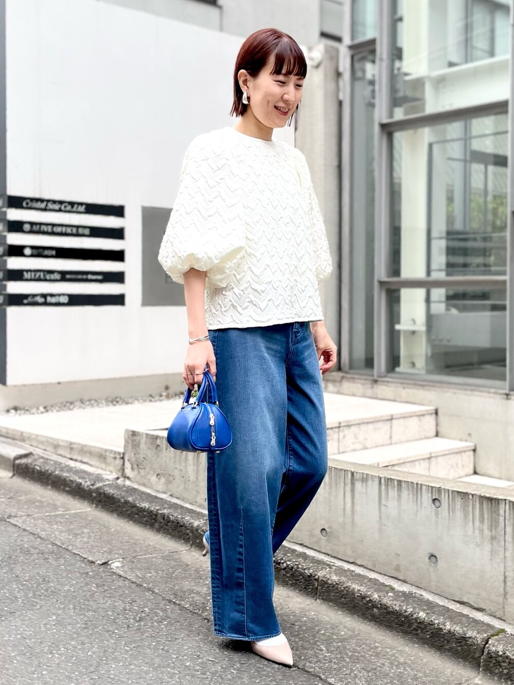 ブルー系のボストンバッグ、ブルー系のデニムパンツ、ホワイト系のシャツ/ブラウスを着用したレディースの冬コーディネートの4枚目の写真