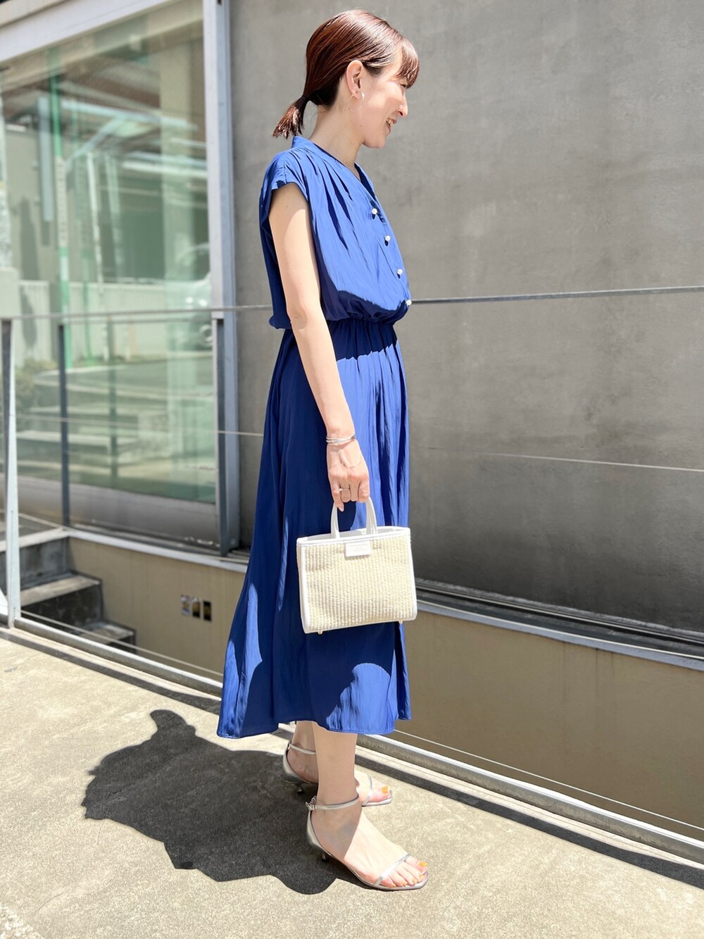 ホワイト系のトートバッグ、ブルー系のワンピース、ホワイト系のサンダルを着用したレディースの春コーディネートの6枚目の写真