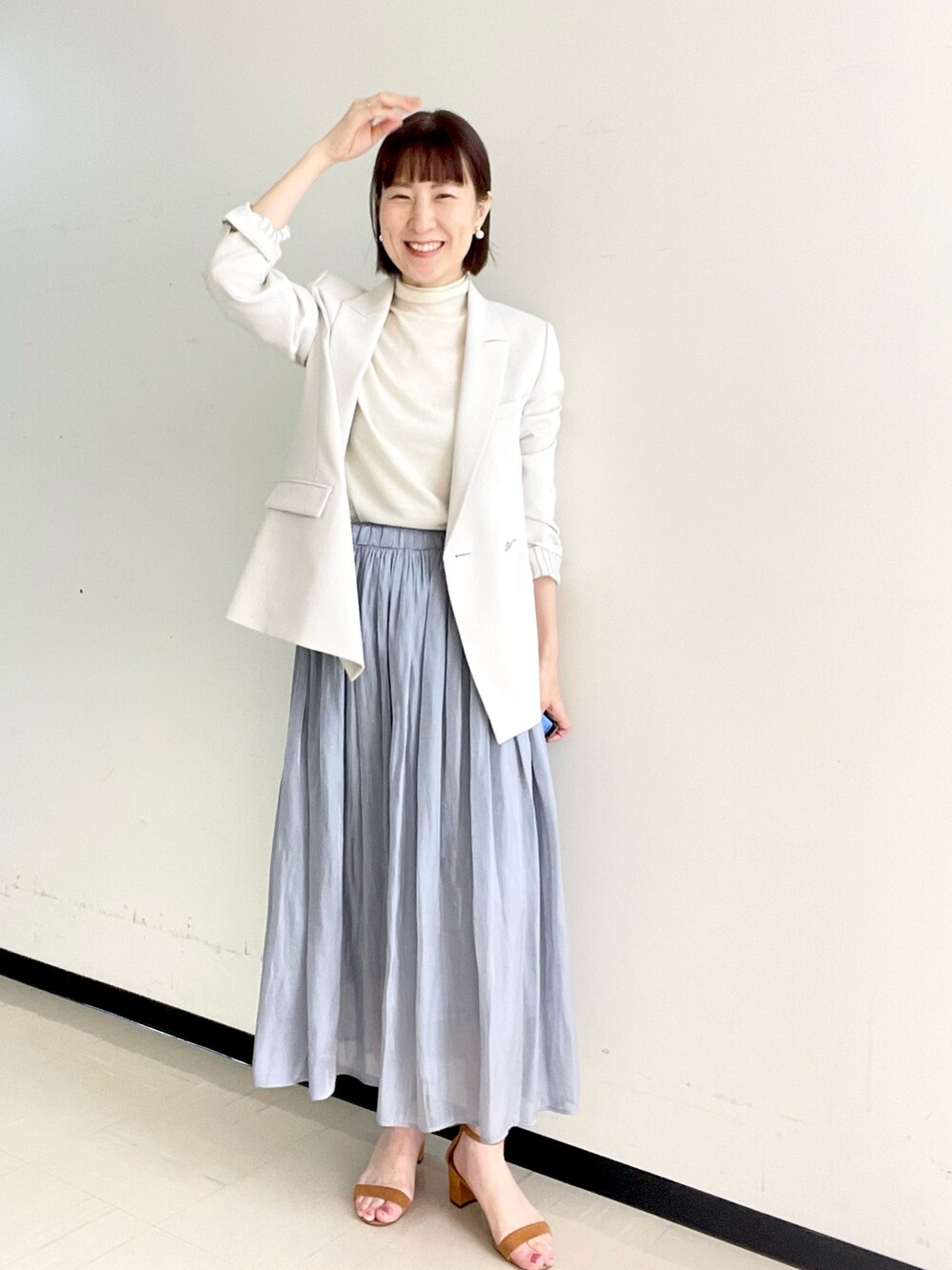 ホワイト系のニット/セーター、ベージュ系のテーラードジャケット、ゴールド系のイヤリングを着用したレディースの冬コーディネートの5枚目の写真