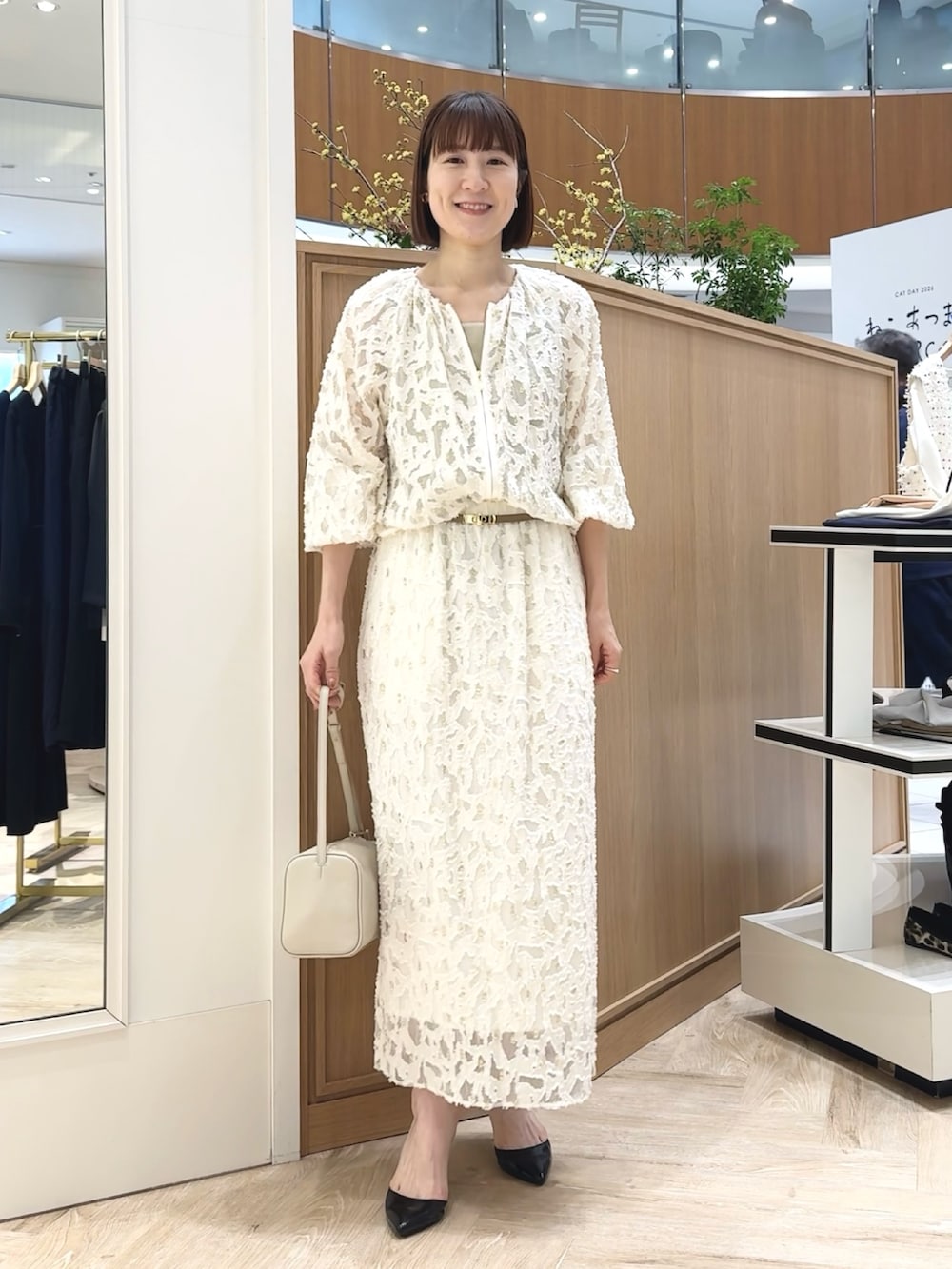 ホワイト系のショルダーバッグ、ゴールド系のタンクトップ、ホワイト系のブルゾンを着用したレディースの冬コーディネートの4枚目の写真