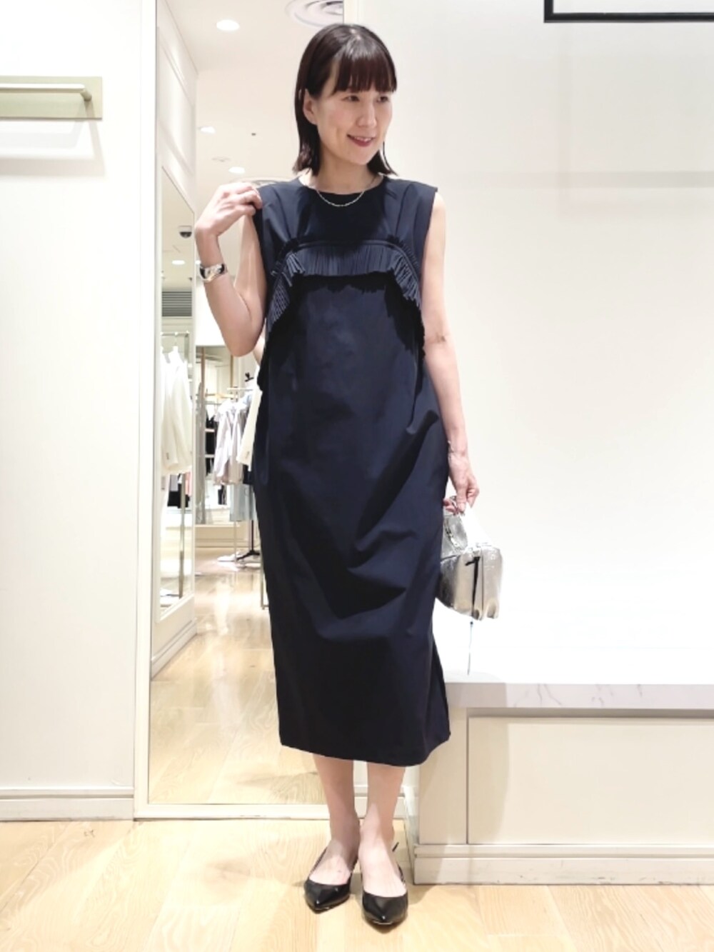 ブラック系のパンプス、ブルー系のワンピース、シルバー系のネックレスを着用したレディースの春コーディネートの5枚目の写真