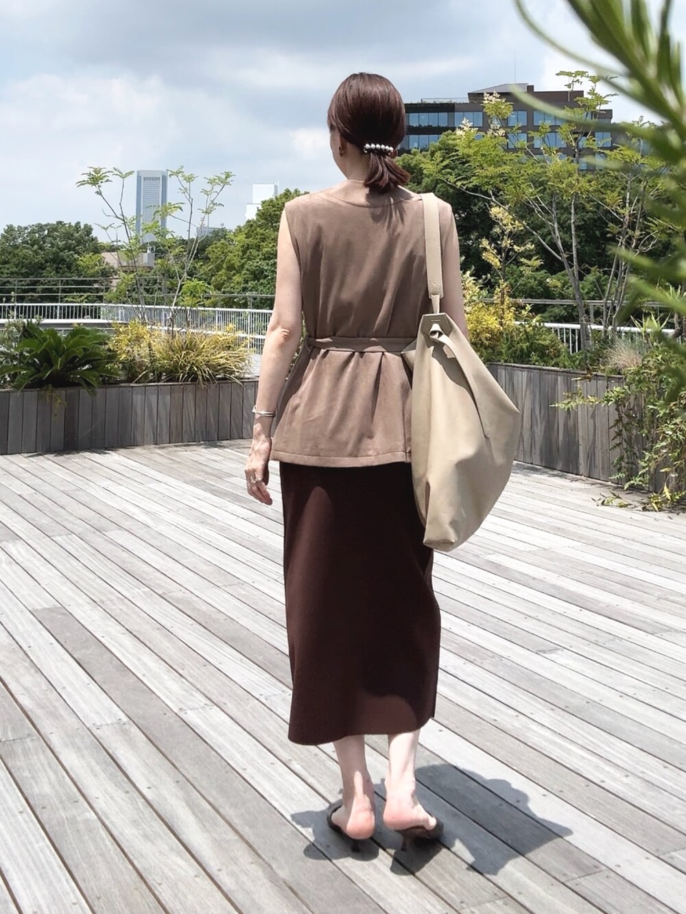 ゴールド系のタンクトップ、ベージュ系のベスト、ベージュ系のショルダーバッグを着用したレディースの秋コーディネートの3枚目の写真